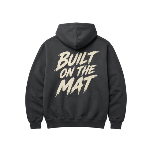 A dark gray hoodie shown from the back, featuring a large cream-colored graphic text print that reads 'BUILT ON THE MAT' in a stylized brushstroke font.